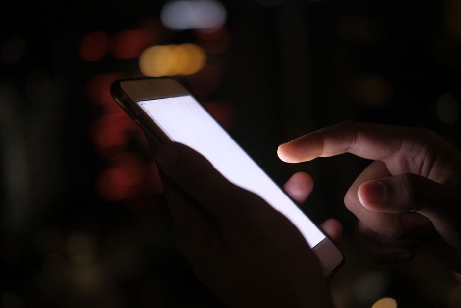 Person using a smartphone in the dark, representing mobile VPN use